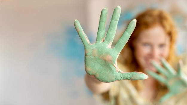 Close-up green paint on woman's palms