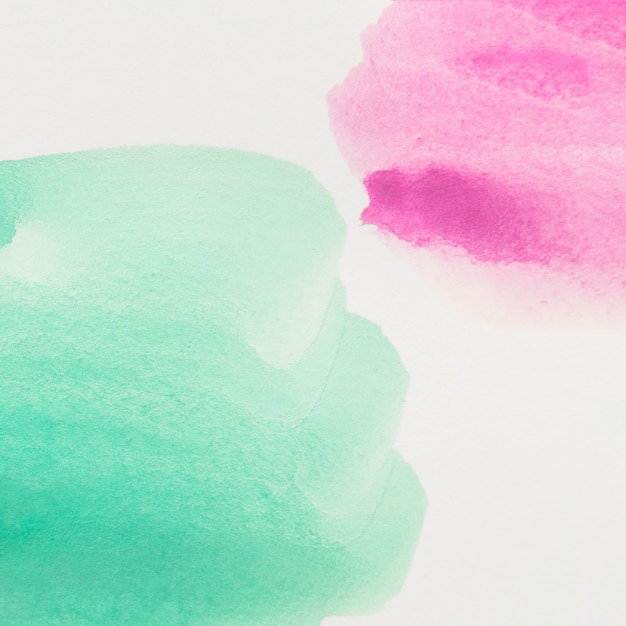 Close-up of green and pink watercolor paint on white background