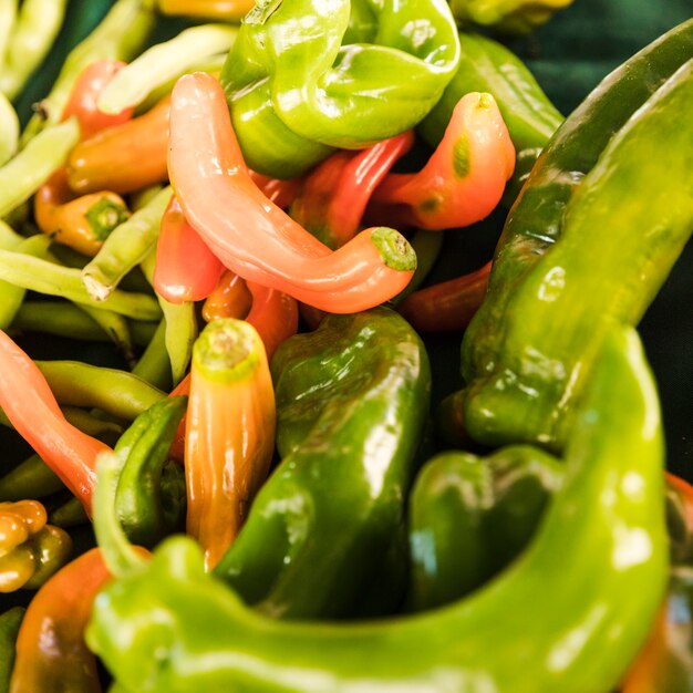 Конец-вверх зеленых и красных перцев на стойле овощного рынка