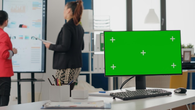 비즈니스 사무실에서 모니터에 녹색 화면 배경 닫습니다. 시작 회사 작업에 사용되는 책상에 빈 크로마 키와 격리된 모의 템플릿이 있는 컴퓨터. 크로마키