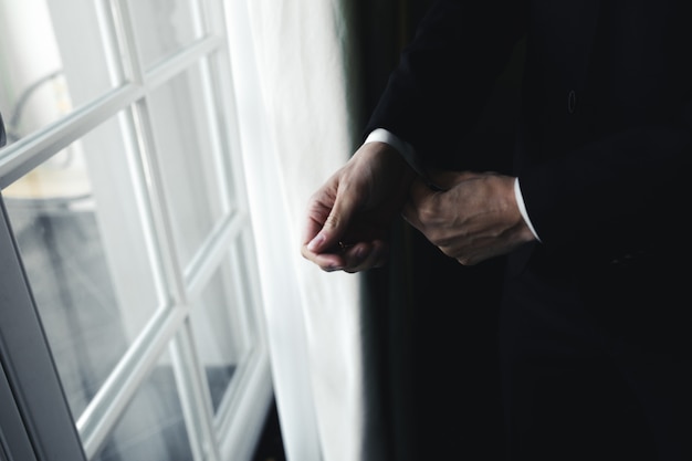 Close-up of groom fastening the caff