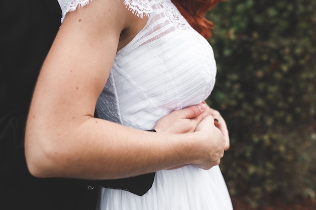 Close-up of groom's hands on his wife's belly