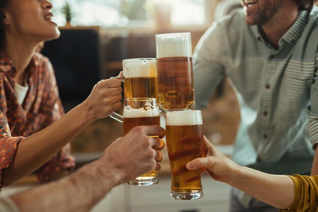 Close-up of group of people toasting with beer at home party.