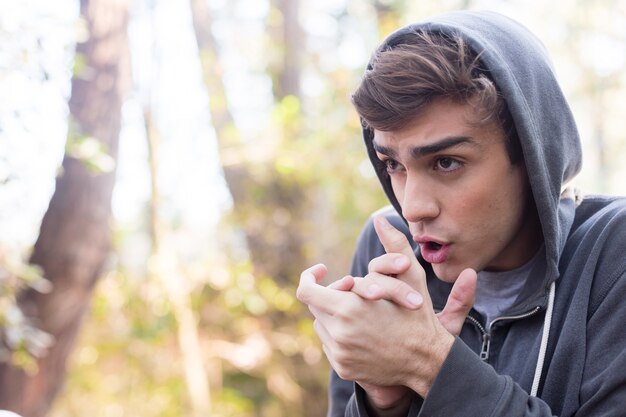 Close-up of guy with a hooded sweatshirt and warming his hands