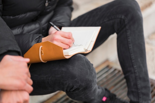 Close-up guy writing in notebook