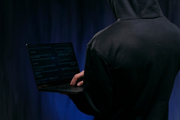 Бесплатное фото Крупным планом хакер, держащий ноутбук