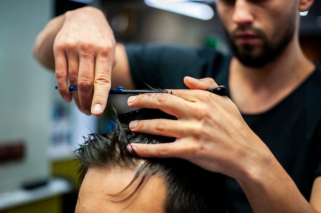 close-up of hairstylist cutting customer hair