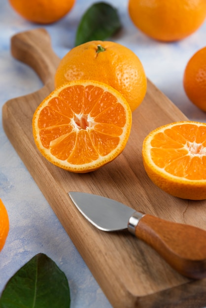 Close up of half cut mandarin on wooden cutting board