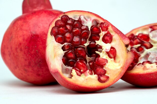 Close up of half-divided pomegranates in white background
