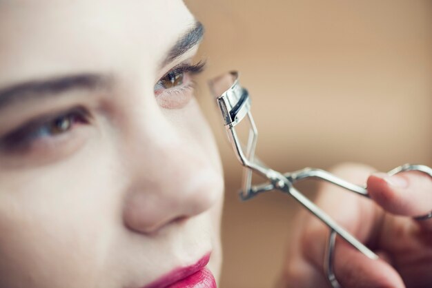 Close-up hand curling eyelashes of model
