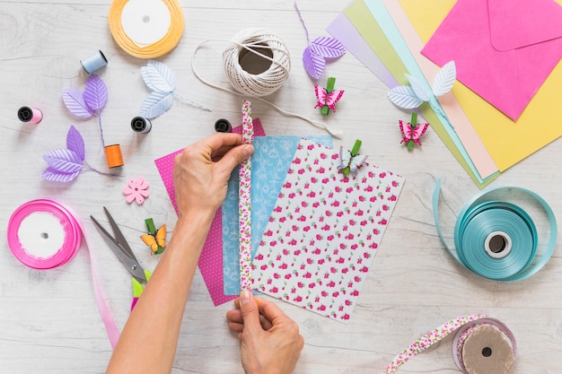 Close-up of hand decorating ribbon on scrapbooking card on textured backdrop