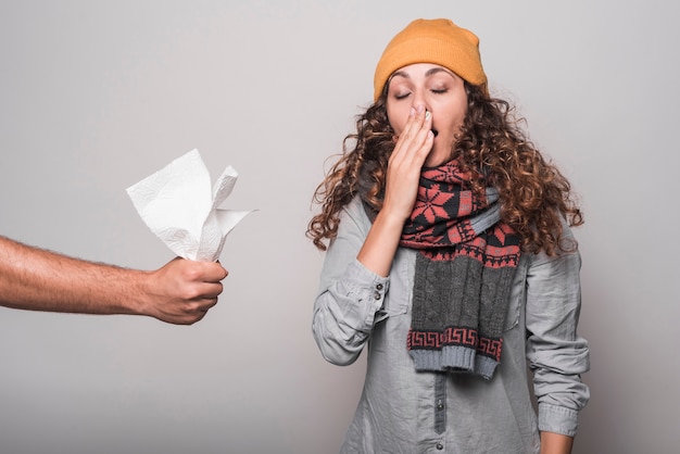 Close-up of hand giving tissue paper to sick woman suffering from cold and flu