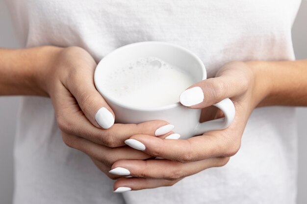 Close-up of hand held mug of milk