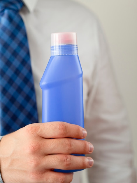 Close-up hand holding blue detergent bottle mock-up