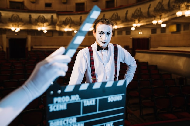 Close-up of hand holding clapperboard in front of male mime