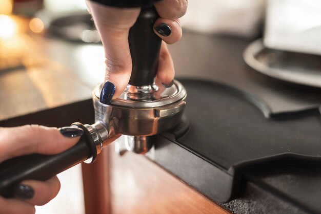 Close-up hand holding coffee filter and tamper