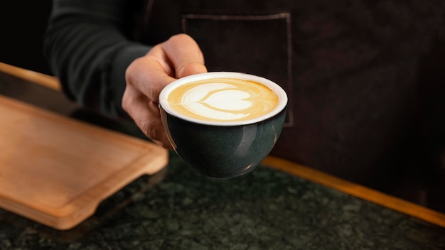 Close-up hand holding coffee with milk cream