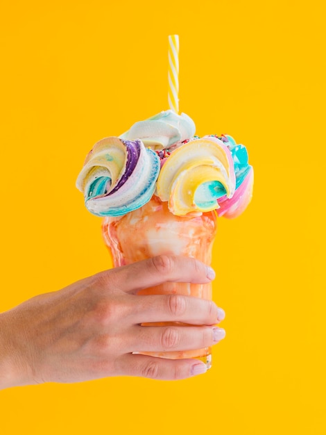 Free photo close-up hand holding colorful milkshake