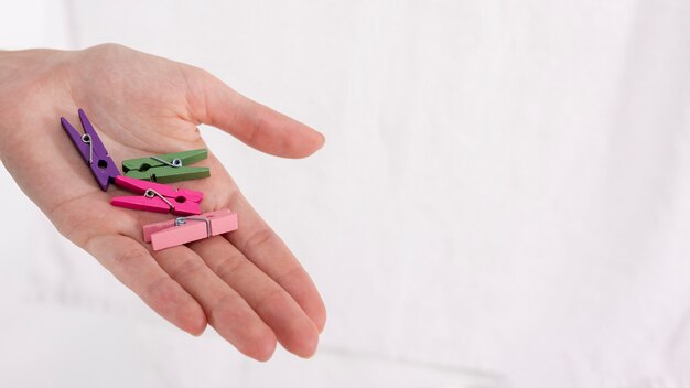 Close-up hand holding colourful clothes-pins