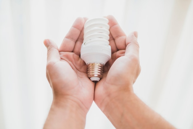 Primo piano della mano che tiene la lampadina fluorescente compatta