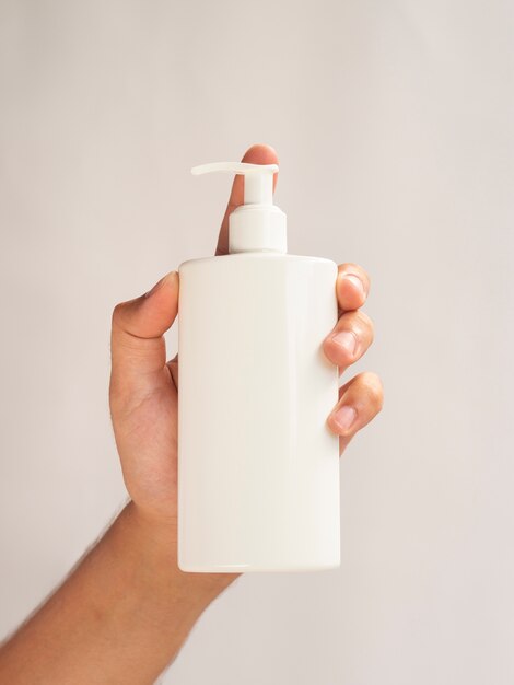 Close-up hand holding cream bottle mock-up