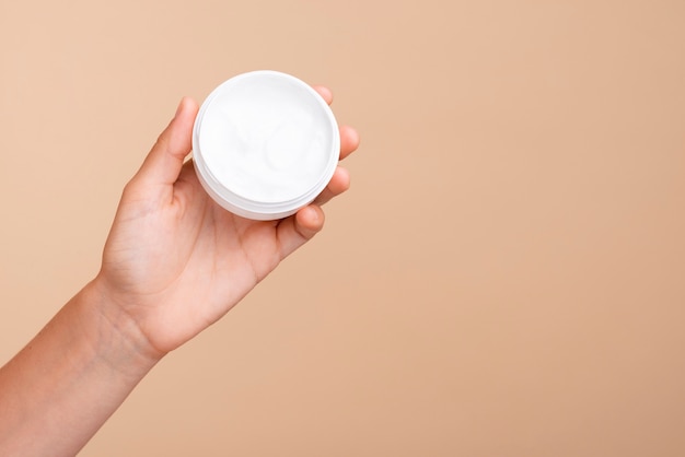 Close-up hand holding cream jar with copy-space