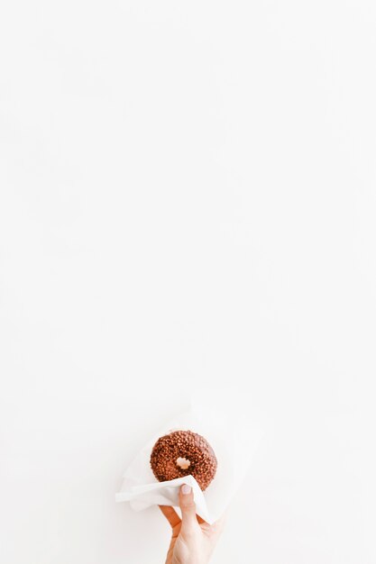 Close-up of hand holding donut with tissue paper