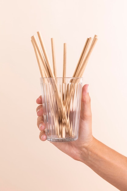 Close-up hand holding glass with straws