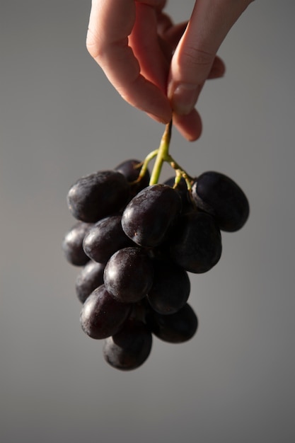 Foto gratuita chiuda sulla mano che tiene l'uva per l'estate