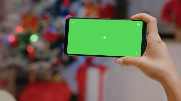 Close up of hand holding horizontal green screen on smartphone