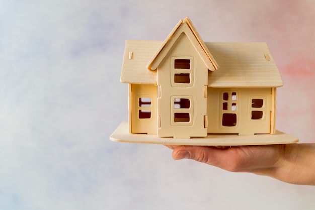 Close-up of hand holding house model against textured background