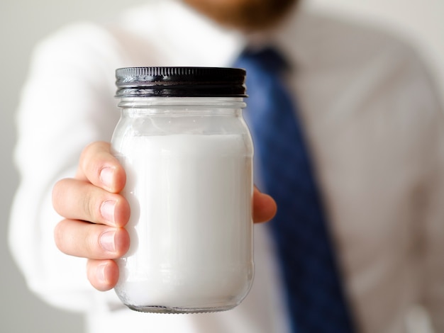 Free photo close-up hand holding a jar of sugar mock-up