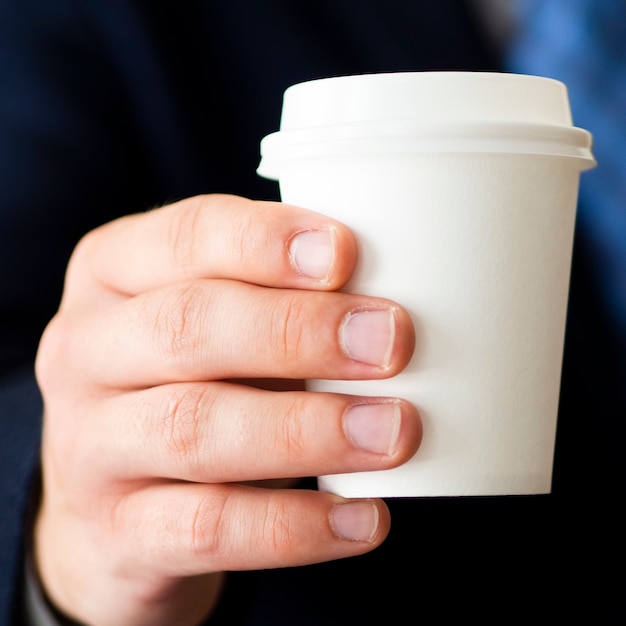 Foto gratuita mano del primo piano che tiene piccolo modello della tazza di caffè