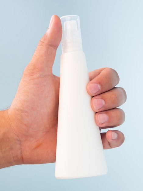 Close-up hand holding lotion bottle mock-up