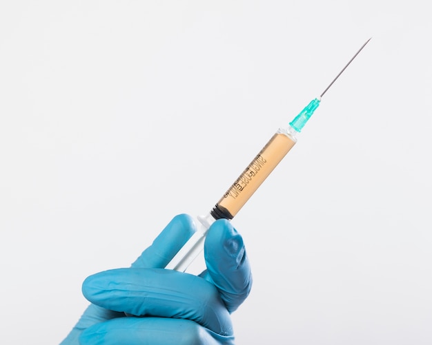 Close-up hand holding medical syringe