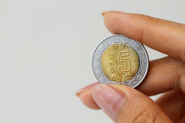 Крупным планом рука держит мексиканскую монету