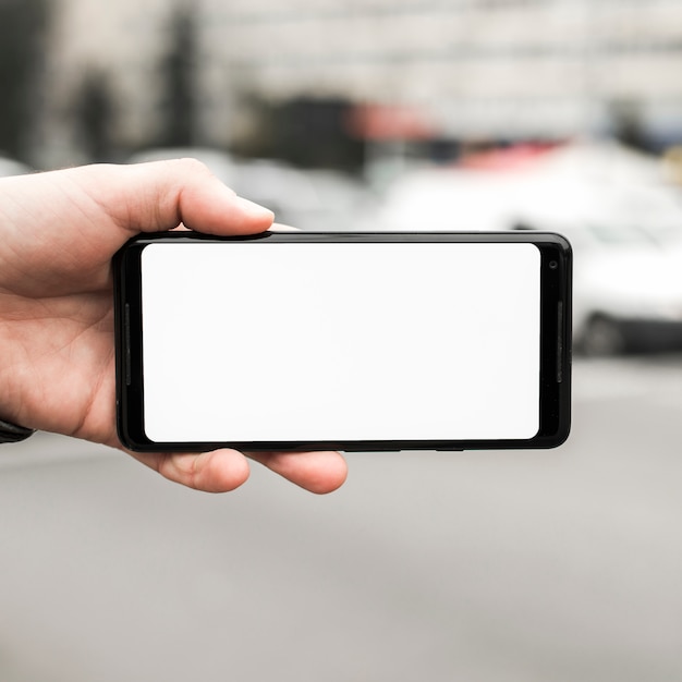 Close-up of hand holding mobile phone showing blank white screen