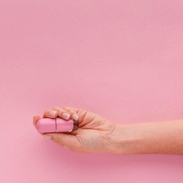 Close-up hand holding pink nail polish