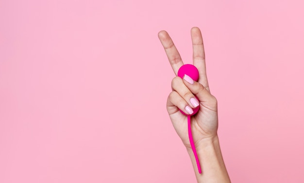Крупным планом рука держит розовую секс-игрушку