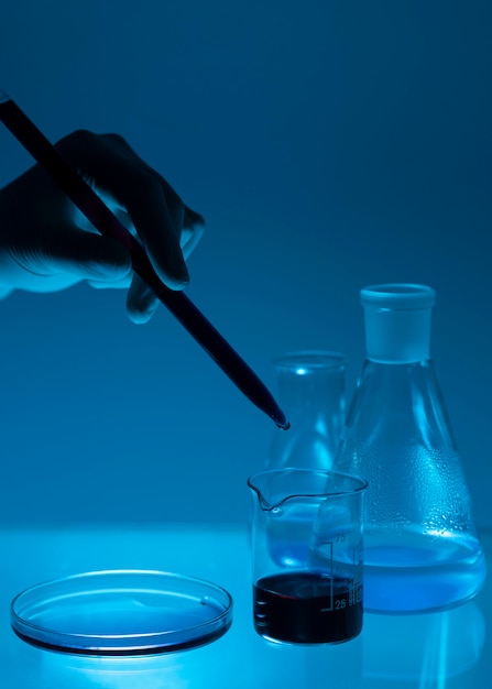 Close-up hand holding pipette in low light