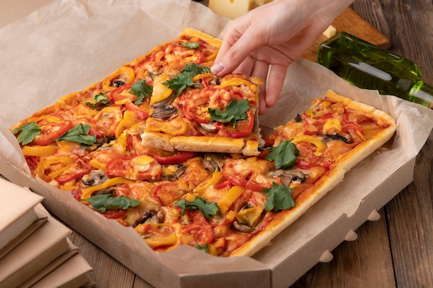 Free photo close up hand holding pizza slice