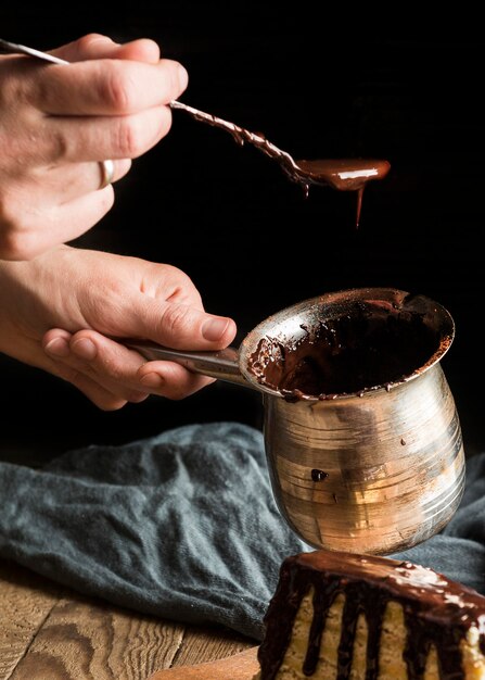 Close-up hand holding pot with hot chocolate and spoon