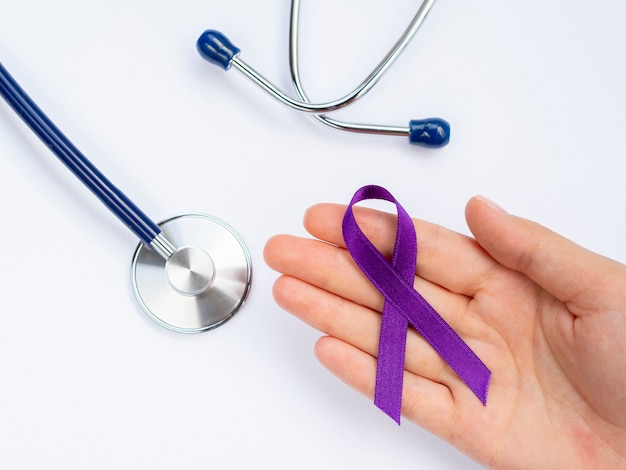 Close-up hand holding purple ribbon with stethoscope