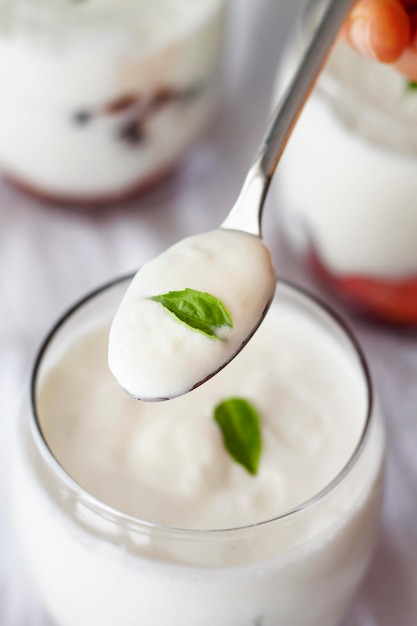 Close-up hand holding spoon with yogurt