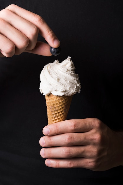 Close-up hand holding tasty ice cream with berry