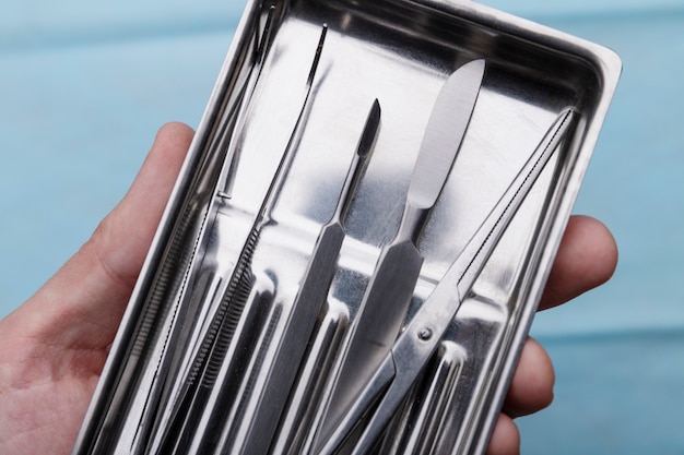 Free photo close-up of hand holding tray with medical scalpel and tools