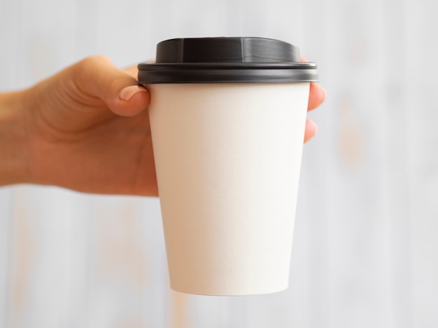 Mano del primo piano che ostacola la tazza di caffè