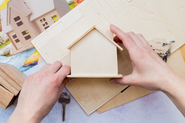 Крупным планом руки, держащей деревянную миниатюрную модель дома