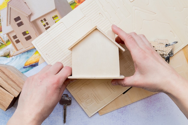 Close-up of hand holding wooden miniature house model