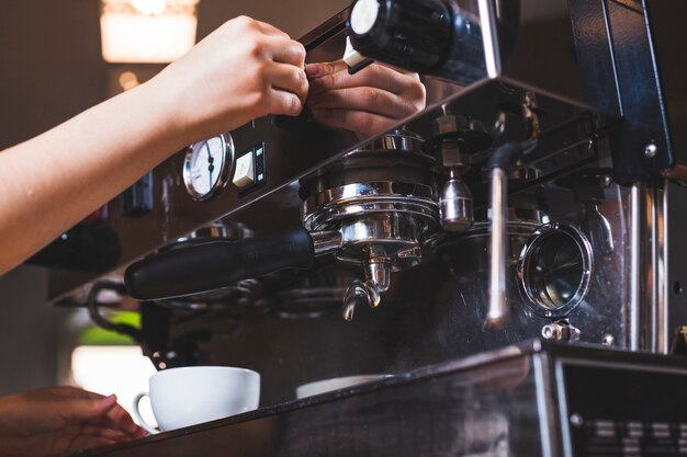 Close-up of hand making coffee in coffee shop